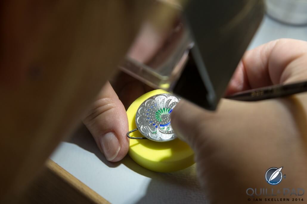 The dial blank is then engraved and gradually coated in multiple layers of colored enamel
