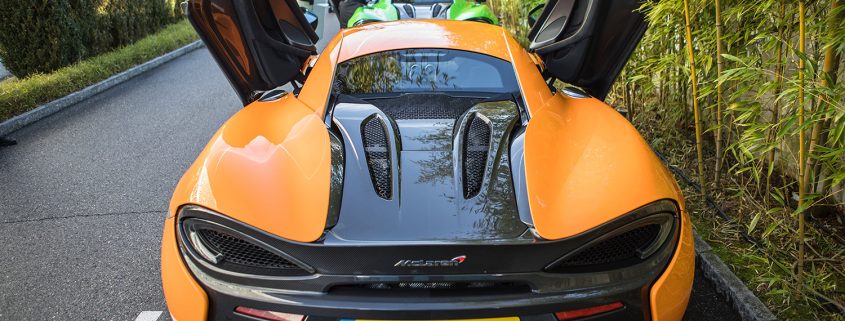 Doors wide open: view from the back of parked McLaren 570s supercars
